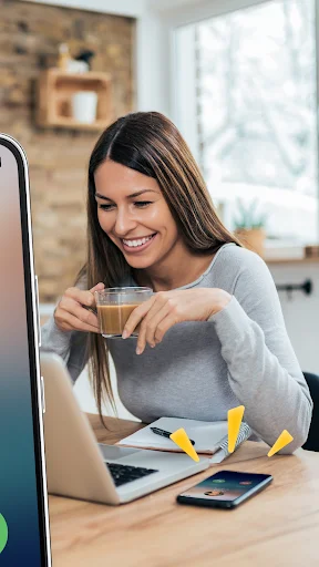 Woman smiling while using laptop as Caller Name Announcer identifies incoming calls on her phone nearby